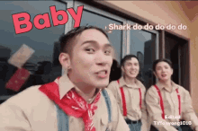 a group of young men are standing in front of a building and one of them is wearing a red bandana and suspenders .