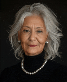 a woman with gray hair wearing a pearl necklace and earrings