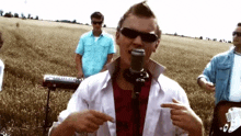 a man singing into a microphone in a field with other men