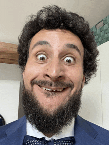 a man with a beard wearing a blue suit and bow tie makes a funny face