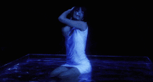 a woman in a white dress is kneeling in a pool of water