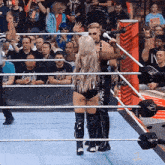 a woman in a wrestling ring stands next to a man in a black outfit