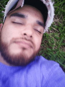 a man with a beard and hat is laying in the grass