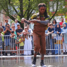 a man in overalls is dancing in a puddle in front of a crowd with a sign that says snvco