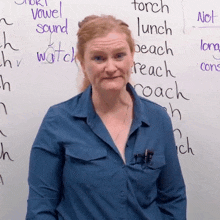 a woman in a blue shirt stands in front of a white board with words such as vowel sound and torch written on it