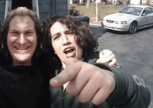 a man pointing at another man in front of a mustang