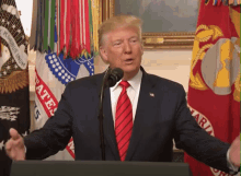 a man in a suit and tie stands at a podium in front of a flag that says pluribus unum