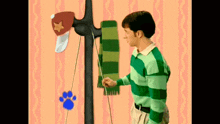 a man in a blue and green striped shirt is holding a green scarf in front of a clothes rack .