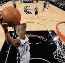 a man in a spurs jersey is holding a basketball above his head