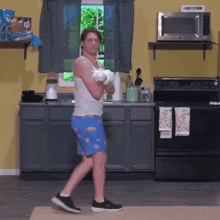 a man in boxing gloves is standing in a kitchen .