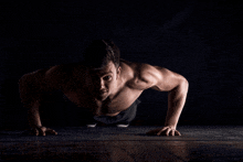 a shirtless man is doing push ups on the floor in the dark