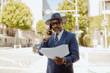 a man in a suit and hat talking on a cell phone