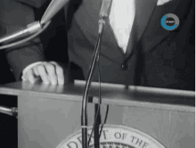 a man stands at a podium in front of a microphone that says department of the united states of america