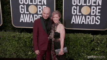 a man and a woman pose on a red carpet in front of a sign that says golden globe awards