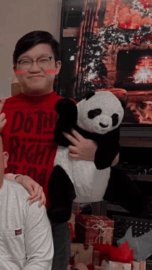 a boy wearing a red shirt that says do it right is holding a stuffed panda bear