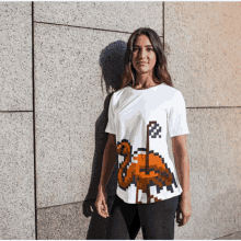 a woman is wearing a white t-shirt with a pixelated flamingo on it