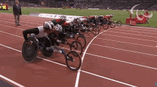 a group of wheelchair racers are lined up on a track and one of them has the number 10 on his helmet