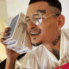 a man with a tattoo on his face is holding a stack of iphones