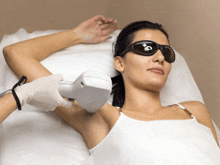 a woman wearing sunglasses is getting a laser hair removal treatment on her arm