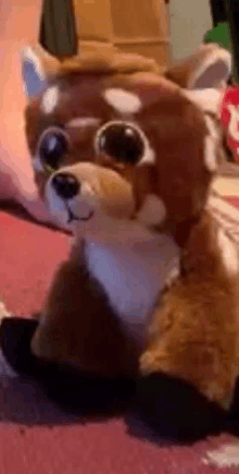 a stuffed animal with big eyes is laying on a carpet .