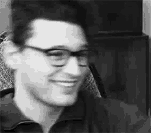 a black and white photo of a man wearing glasses .