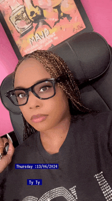 a woman wearing glasses is sitting in front of a framed poster that says maya