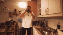 a man taking a picture with a camera in a kitchen with a clock on the wall that shows the time as 10:10