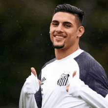 a soccer player is giving a thumbs up sign while wearing a white shirt .