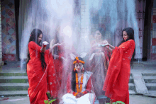 a woman in a white dress is surrounded by three women in red dresses