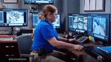 a woman in a blue shirt is sitting at a desk in front of a computer monitor with the hashtag #superstore on it