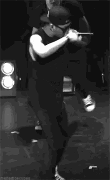 a black and white photo of a man holding a microphone while dancing on a stage .