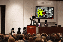 a man stands at a podium at christie 's giving a presentation