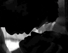 a black and white photo of a man and woman kissing each other .