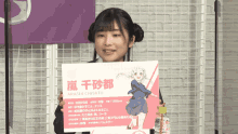 a girl holding a sign that says ' arashi chisato ' on it