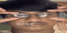 a man wearing glasses is making a funny face and the words smart boi 69 are on his face