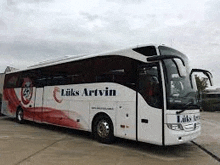 a large white and red bus is parked on the side of the road .