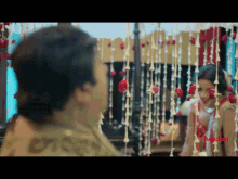 a bride and groom are looking at each other in front of a mirror with flowers hanging from the ceiling