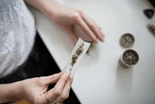 a person is rolling a marijuana cigarette with the letter t on the wrapper