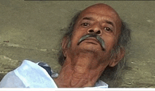 an older man with a mustache is laying on the ground