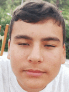 a close up of a boy 's face with a white shirt on