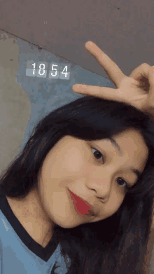 a girl giving a peace sign with the number 1854 above her