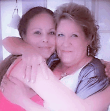 two women are hugging each other in a room and smiling for the camera .