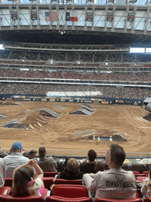 a man in a texas aggie shirt sits in a stadium watching a race