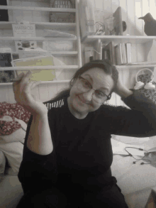 a woman holds a card in front of a shelf with a book called matbrod on it