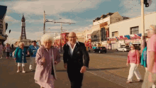 a man and woman are walking down a street in front of a building that says ' candy centre ' on it