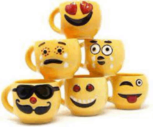 a stack of yellow mugs with smiley faces on them .