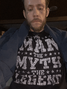 a man with a beard is wearing a black shirt that says man the myth the geek