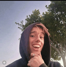 a young man wearing a hooded sweatshirt is smiling