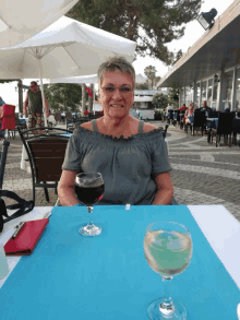 a woman is sitting at a table with a glass of wine