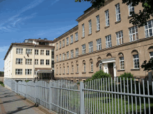 a large building with a fence in front of it and a flag on the top